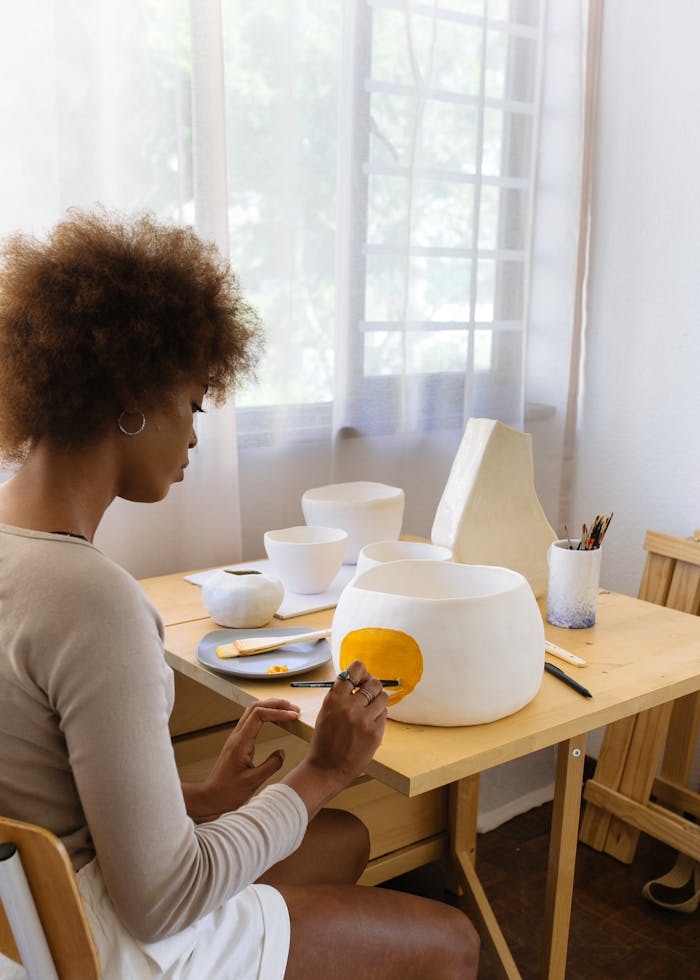 Concentrated black female ceramist paining on handmade clay bowl